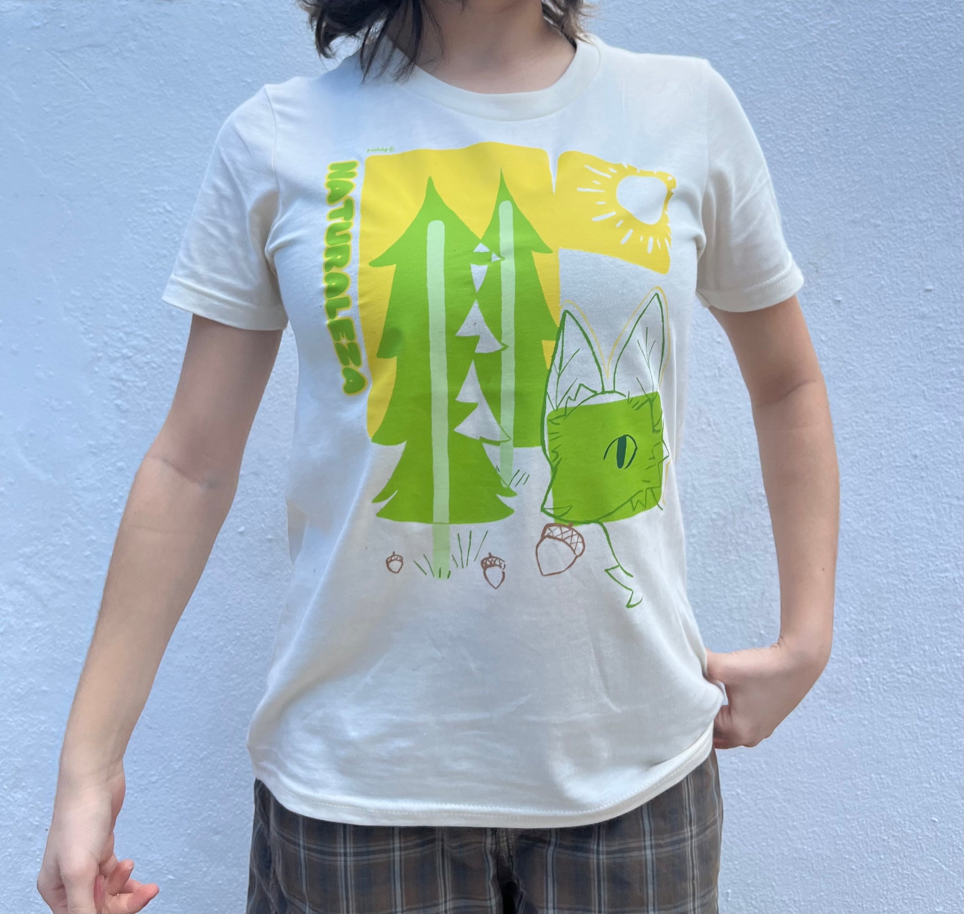 Person wearing a white t-shirt with green graphic design against a blue background